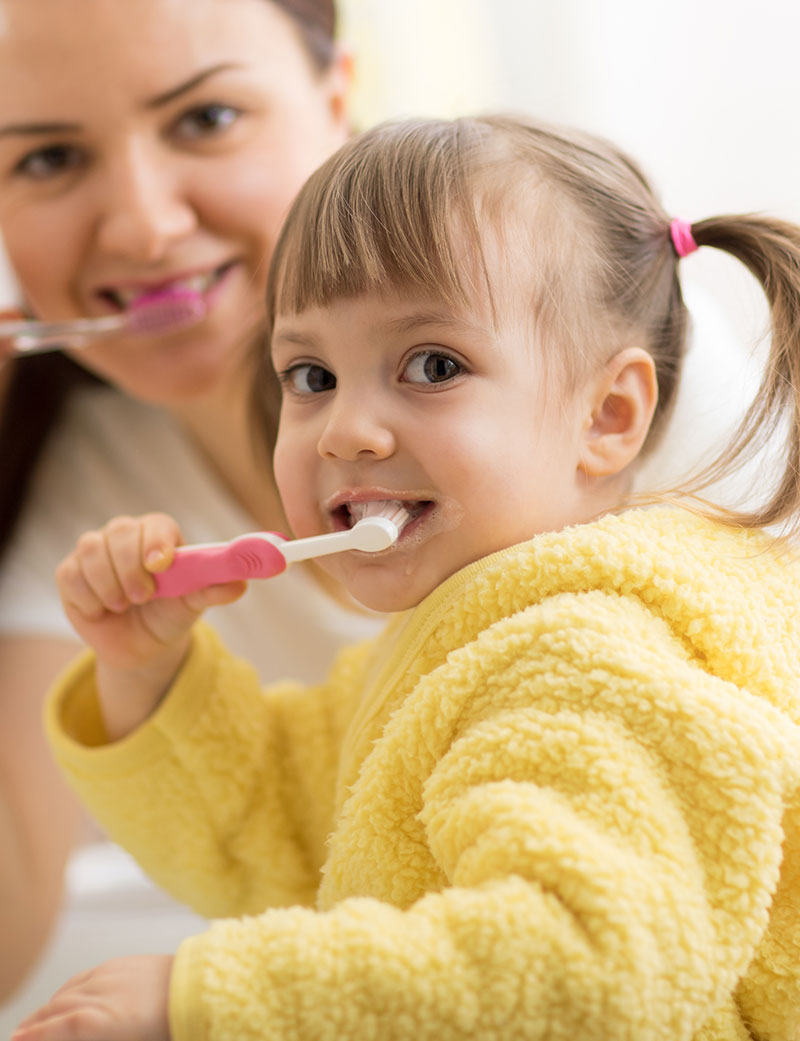 Bambina che lava i denti con la mamma